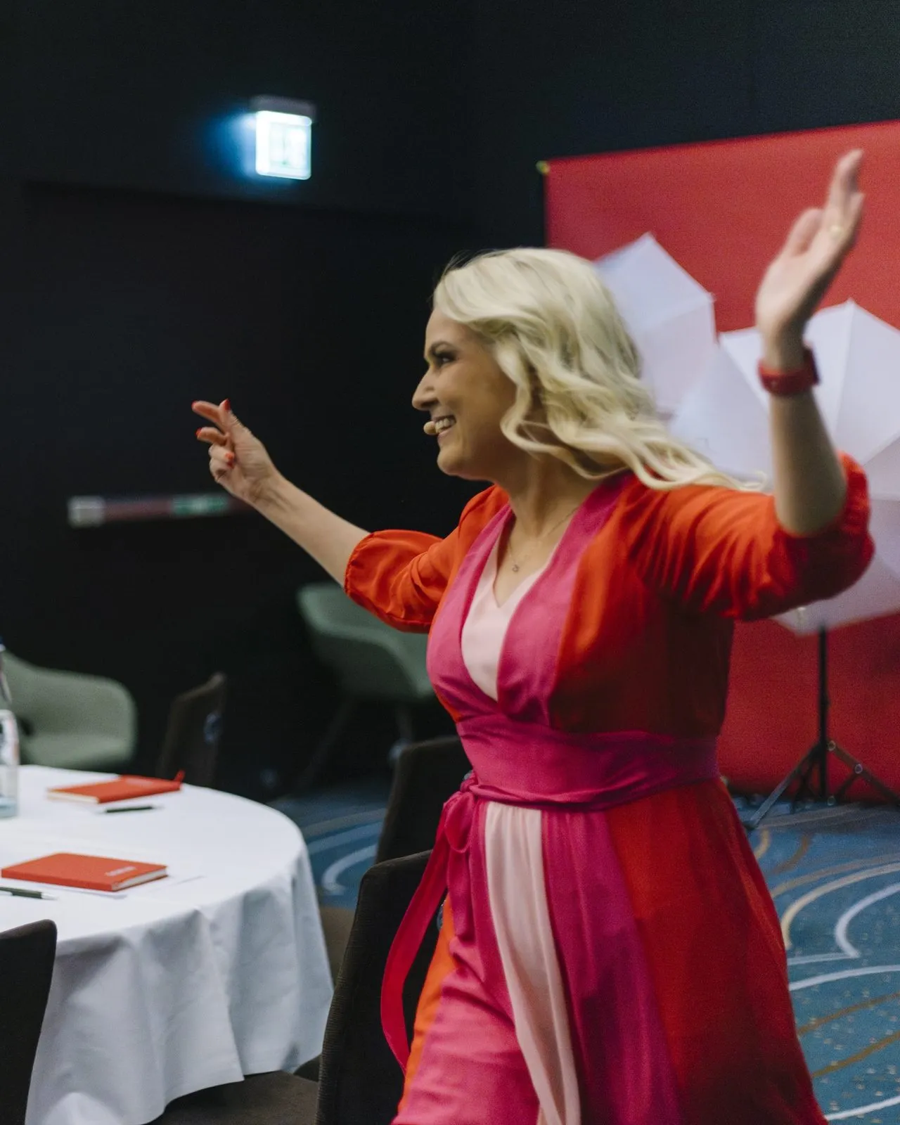 Sigrun with her arms up in front of the red backdrop at SIGRUN Live 2025
